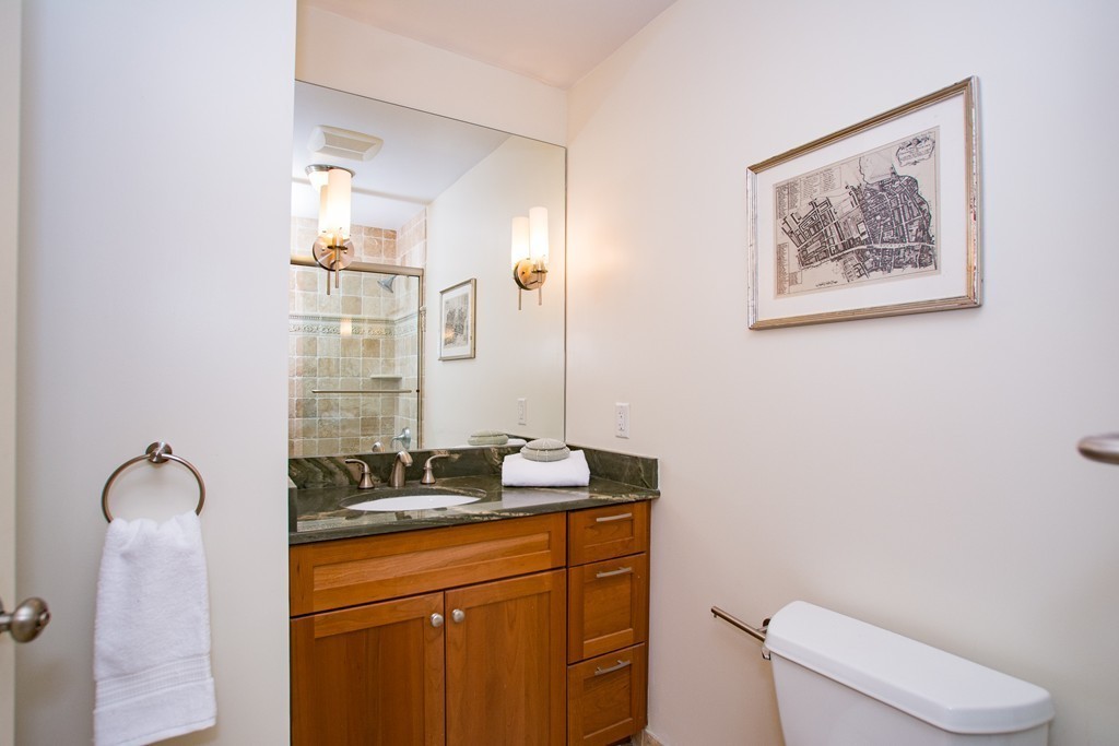 99-105 Broad Street, Unit 8C Boston, MA 02110 - Photo 12 of 28 a bathroom with a granite countertop sink and a mirror