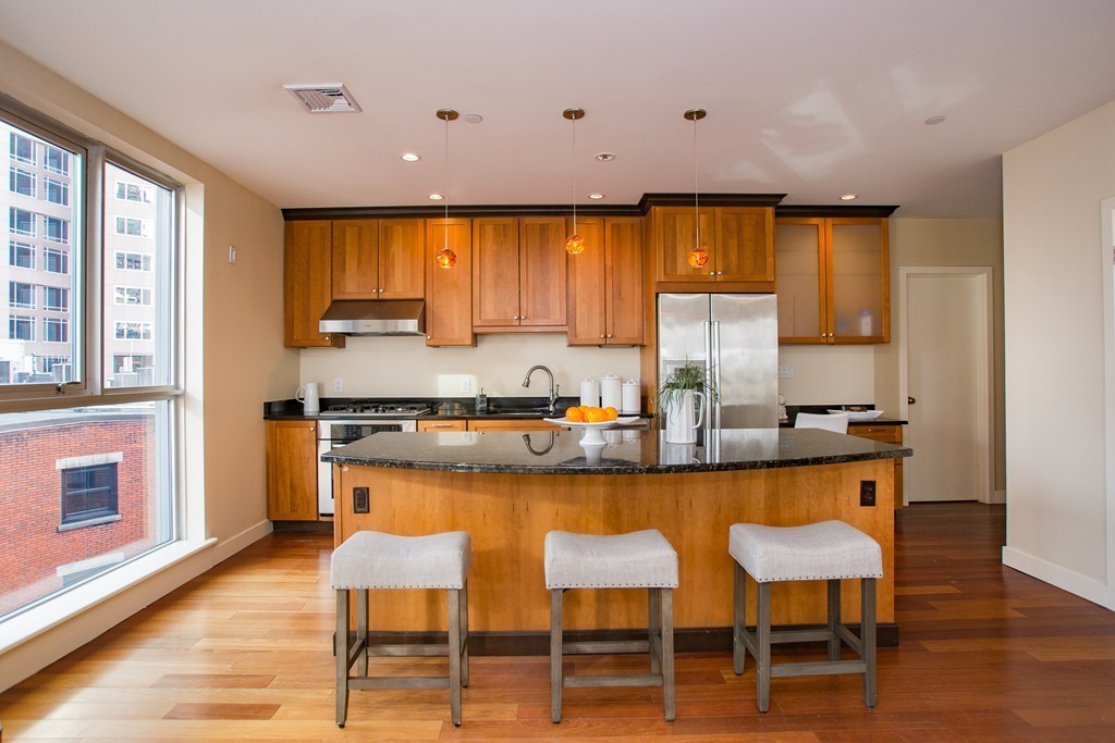 99-105 Broad Street, Unit 8C Boston, MA 02110 - Photo 16 of 28 a kitchen with stainless steel appliances granite countertop table chairs sink and cabinets