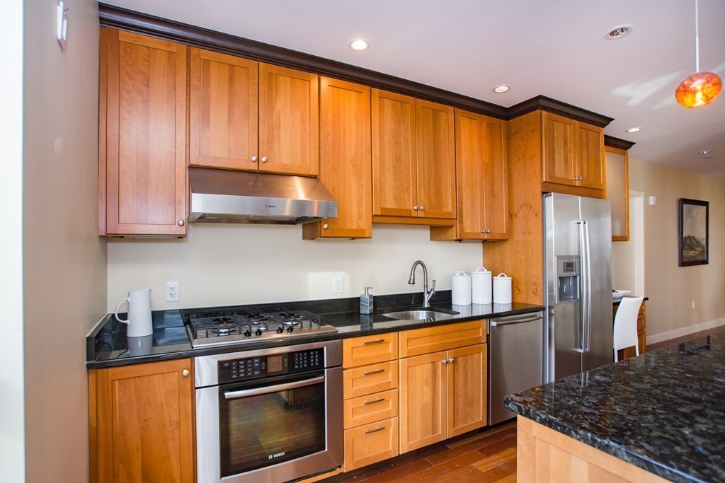 99-105 Broad Street, Unit 8C Boston, MA 02110 - Photo 18 of 28 a kitchen with stainless steel appliances granite countertop a stove a chimney a sink and cabinets