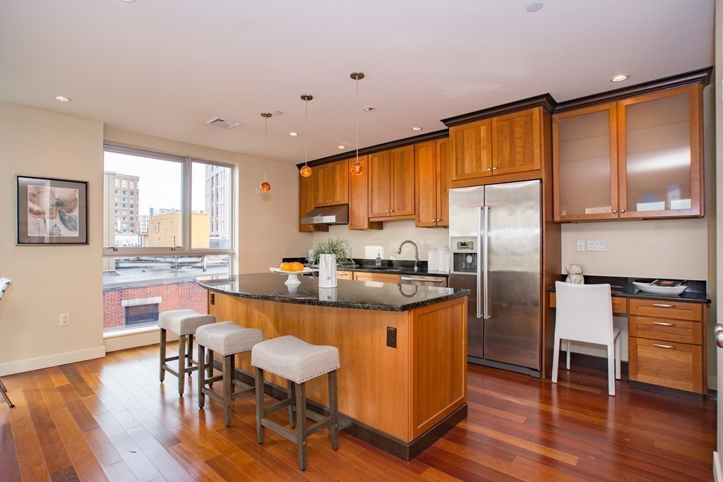 99-105 Broad Street, Unit 8C Boston, MA 02110 - Photo 26 of 28 a kitchen with stainless steel appliances granite countertop a stove refrigerator dining table and chairs