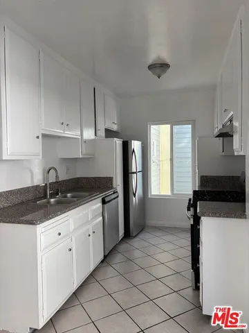 a kitchen with granite countertop a sink a stove and refrigerator