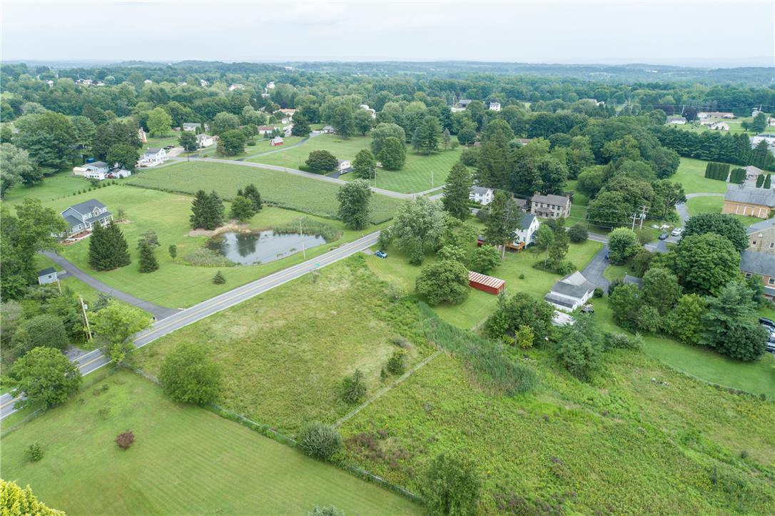 665 Point Phillips Road Bath, PA 18014 - Photo 72 of 73 An aerial perspective reveals a serene countryside setting with scattered homes, verdant fields, and a tranquil pond beside a winding road.