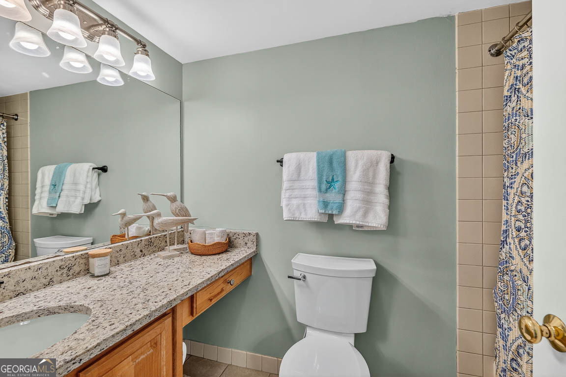 201 Neptune Road, Unit 258 St. Simons, GA 31522 - Photo 17 of 52 a bathroom with a granite countertop toilet sink and mirror