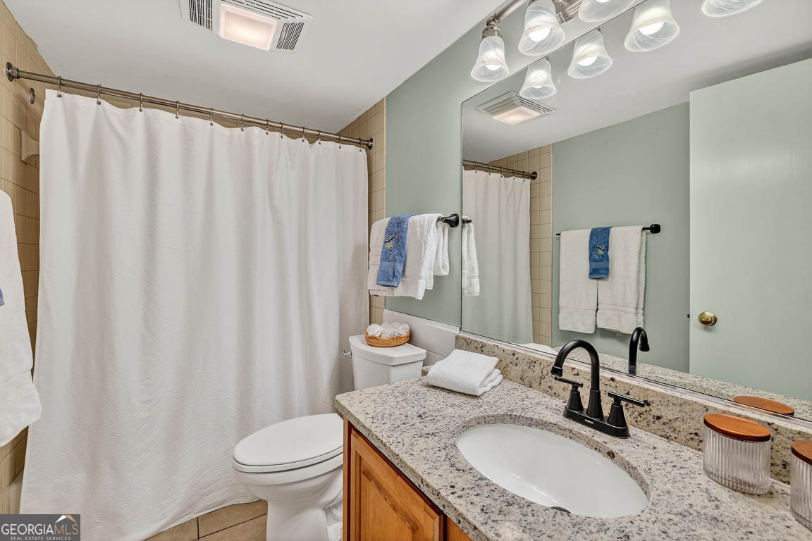 201 Neptune Road, Unit 258 St. Simons, GA 31522 - Photo 23 of 52 a bathroom with a granite countertop sink vanity mirror and toilet