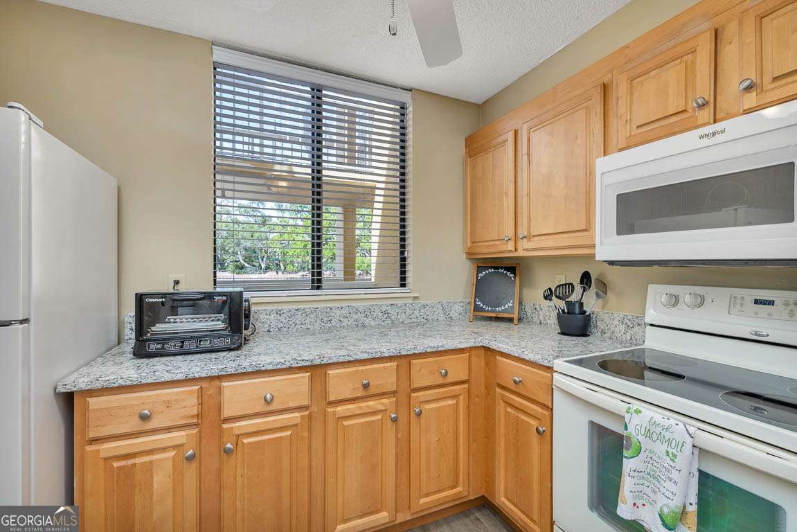 201 Neptune Road, Unit 258 St. Simons, GA 31522 - Photo 24 of 48 a kitchen with granite countertop a sink a stove a microwave cabinets and a window