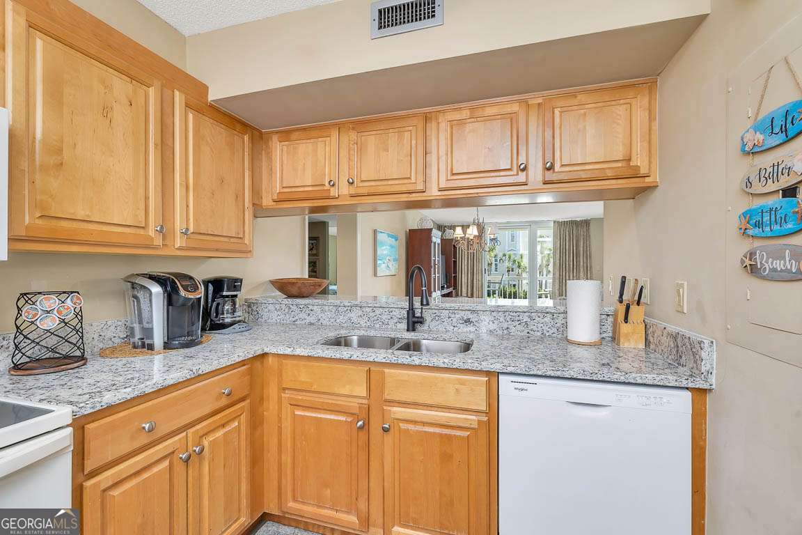 201 Neptune Road, Unit 258 St. Simons, GA 31522 - Photo 25 of 48 a kitchen with granite countertop stainless steel appliances a sink stove and cabinets
