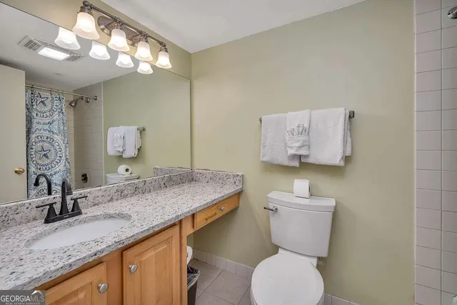 a bathroom with a granite countertop toilet sink and mirror