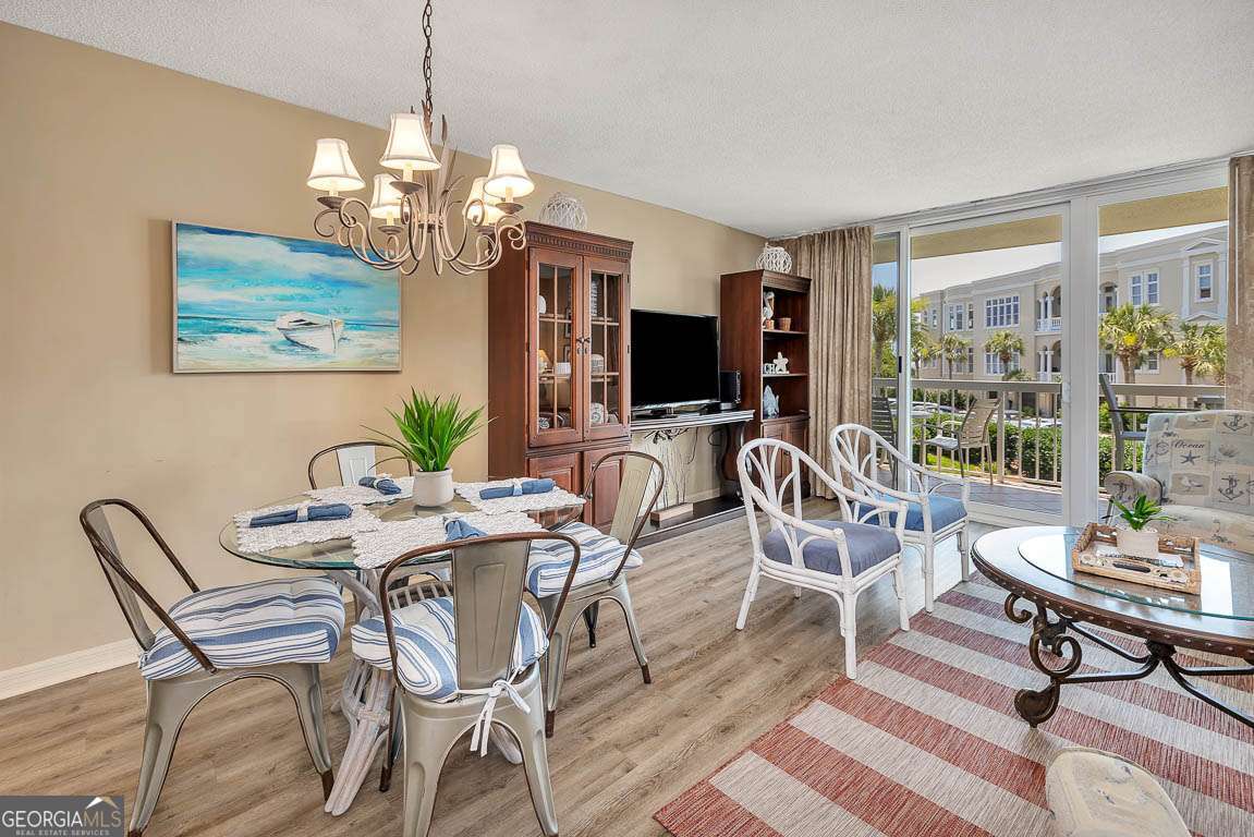 201 Neptune Road, Unit 258 St. Simons, GA 31522 - Photo 5 of 48 a dining room with furniture a chandelier and wooden floor