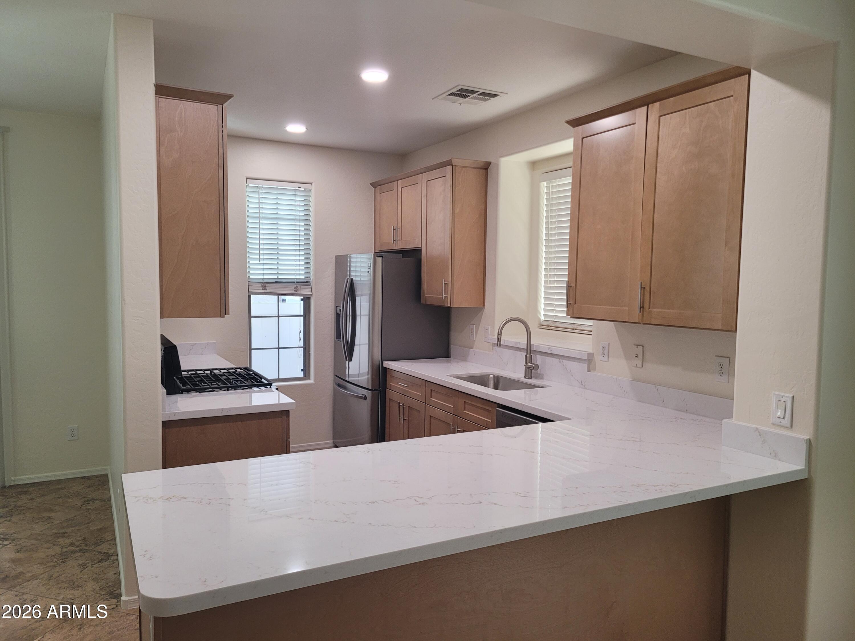 1453 South Sinova Avenue Gilbert, AZ 85296 - Photo 4 of 46 a kitchen with stainless steel appliances granite countertop a sink and a refrigerator