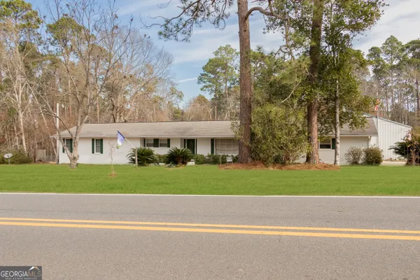 a front view of a house with a garden and trees