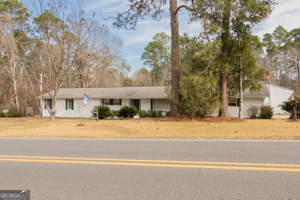 a view of a house with a yard and large trees