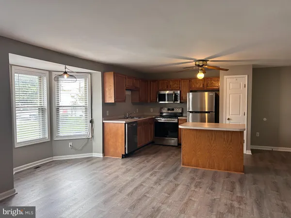 a open kitchen with granite countertop a stove top oven a sink and dishwasher with wooden floor