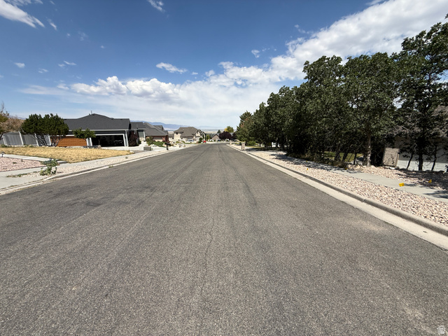 702 Elk Meadow Loop Tooele, UT 84074 - Photo 8 of 9 Residential street featuring a paved roadway, concrete curbing, and gravel landscaping