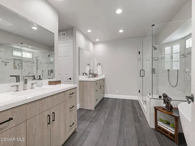 a spacious bathroom with a double vanity sink a large mirror and shower