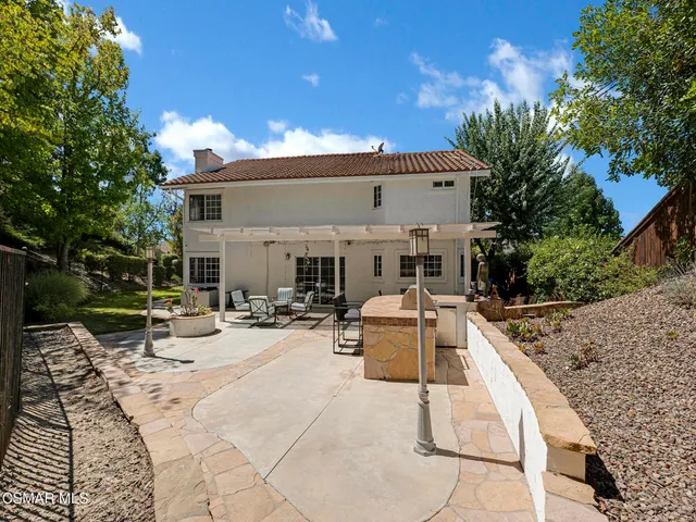 a view of house with patio outdoor seating and covered with trees