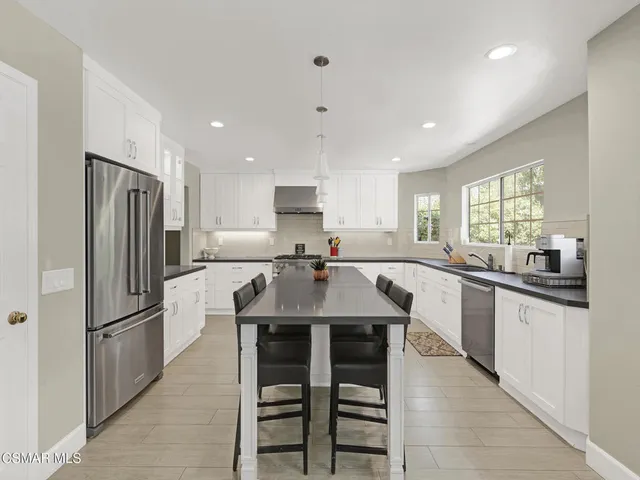 a kitchen with granite countertop a center island stainless steel appliances cabinets and a window