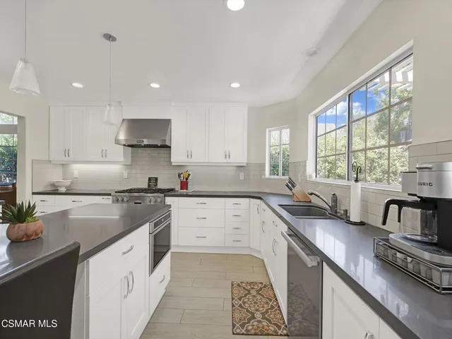a kitchen with kitchen island granite countertop a sink appliances cabinets and a counter top space