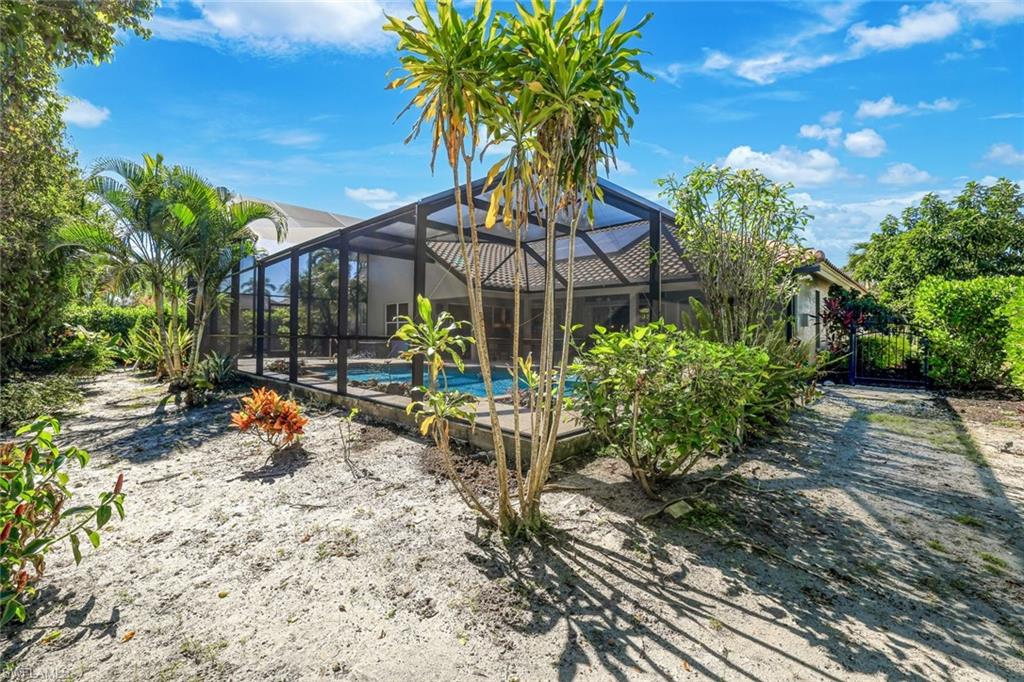 146 Muirfield Circle Naples, FL 34113 - Photo 30 of 31 a backyard of a house with table and chairs under an umbrella