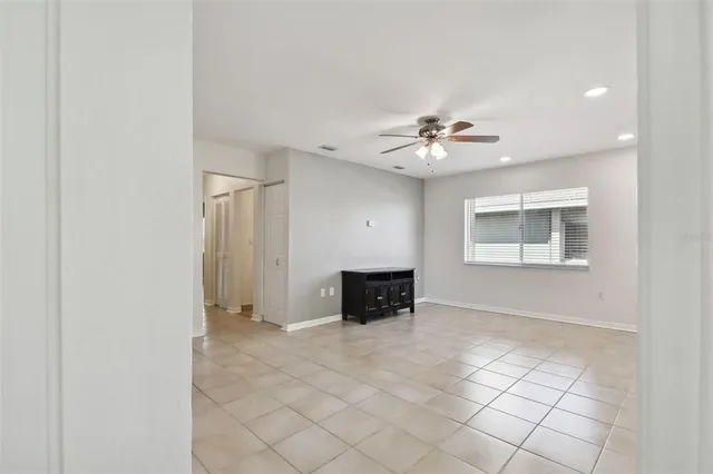 a view of an empty room with a ceiling fan and window