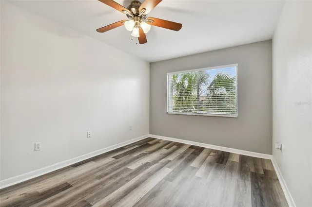 an empty room with a window and ceiling fan