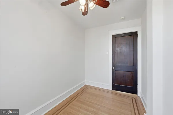 an empty room with a chandelier fan and wooden floor