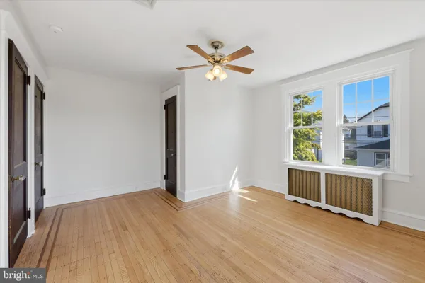 a view of an empty room with window and wooden floor