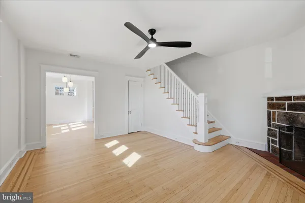 a view of empty room with wooden floor and fan