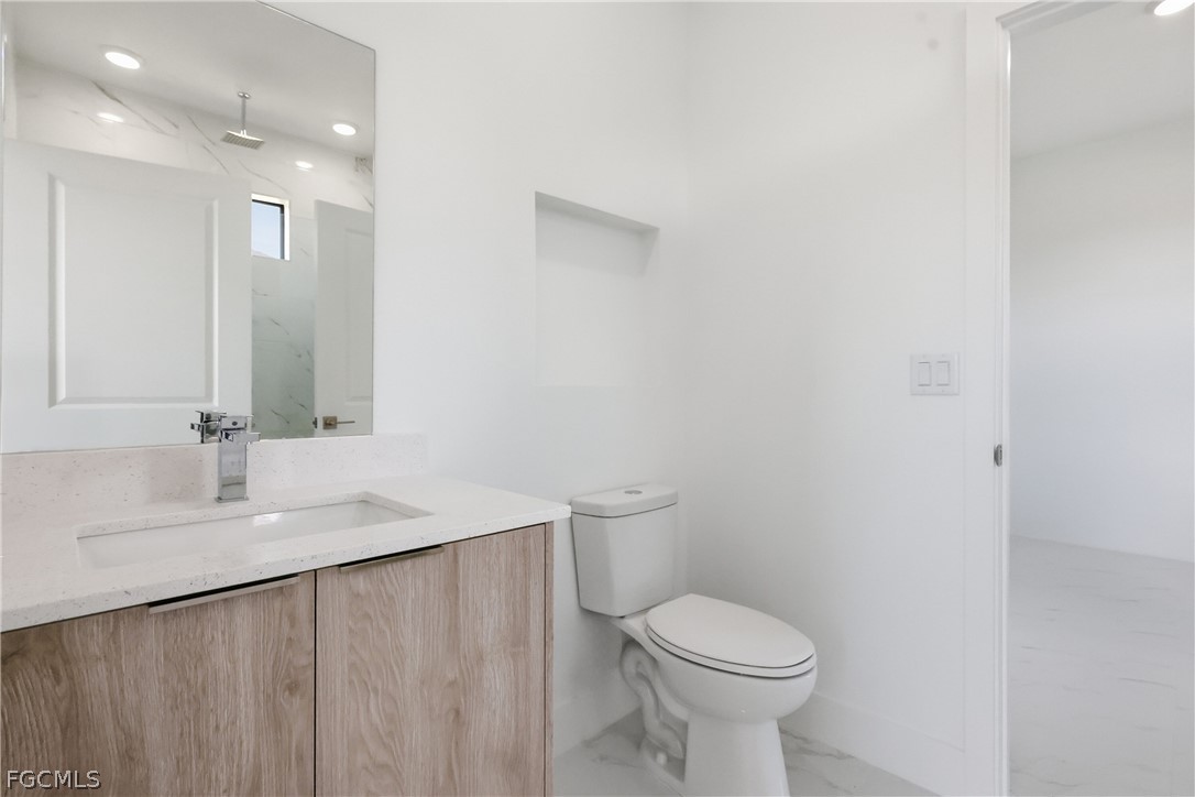 1253 Argosy Road LaBelle, FL 33935 - Photo 24 of 35 a bathroom with a granite countertop sink a toilet and a mirror
