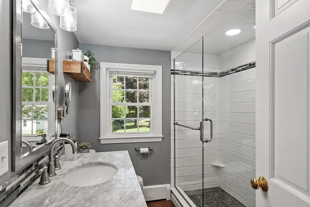 a bathroom with a granite countertop sink a mirror and shower