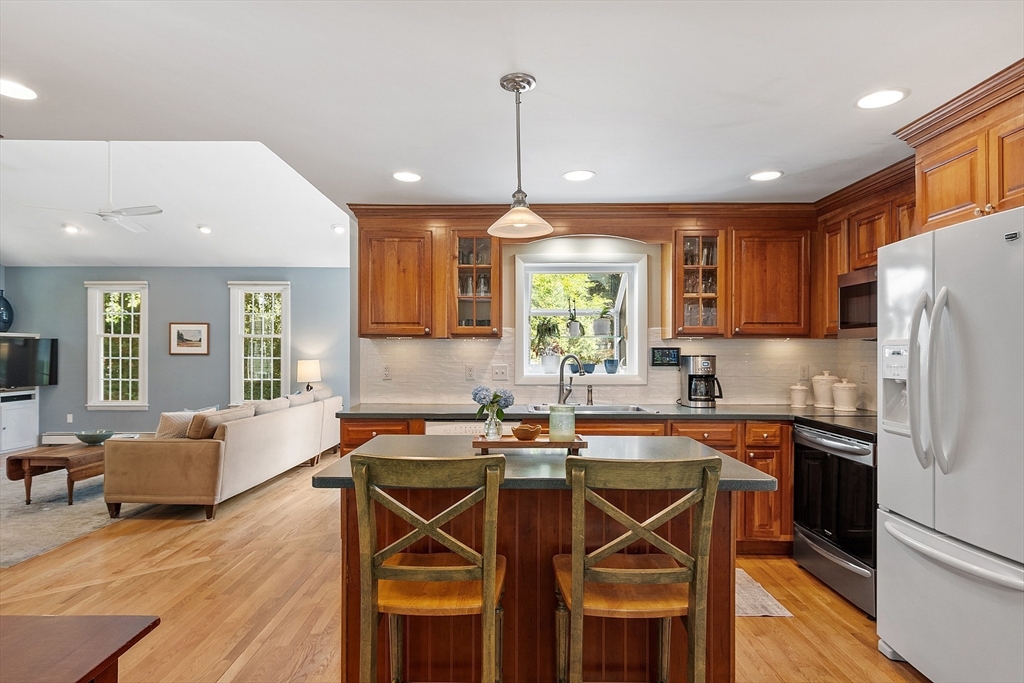 27 Mill Lane Littleton, MA 01460 - Photo 9 of 38 a kitchen with stainless steel appliances granite countertop a dining table chairs refrigerator and sink