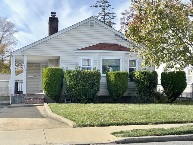 a view of a white house next to a yard and large trees