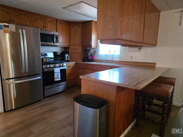 a kitchen with stainless steel appliances a refrigerator a sink a stove and wooden cabinets