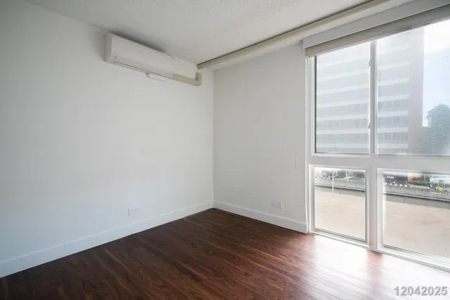 a view of empty room with wooden floor and kitchen view