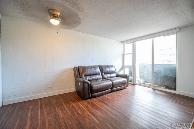 a living room with a couch wooden floor and a large window