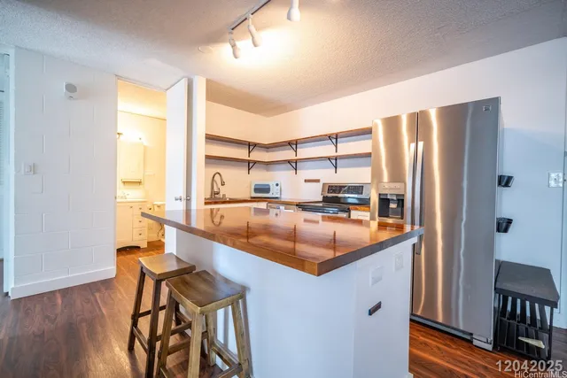 a kitchen with stainless steel appliances granite countertop a refrigerator a sink and a stove with wooden floor