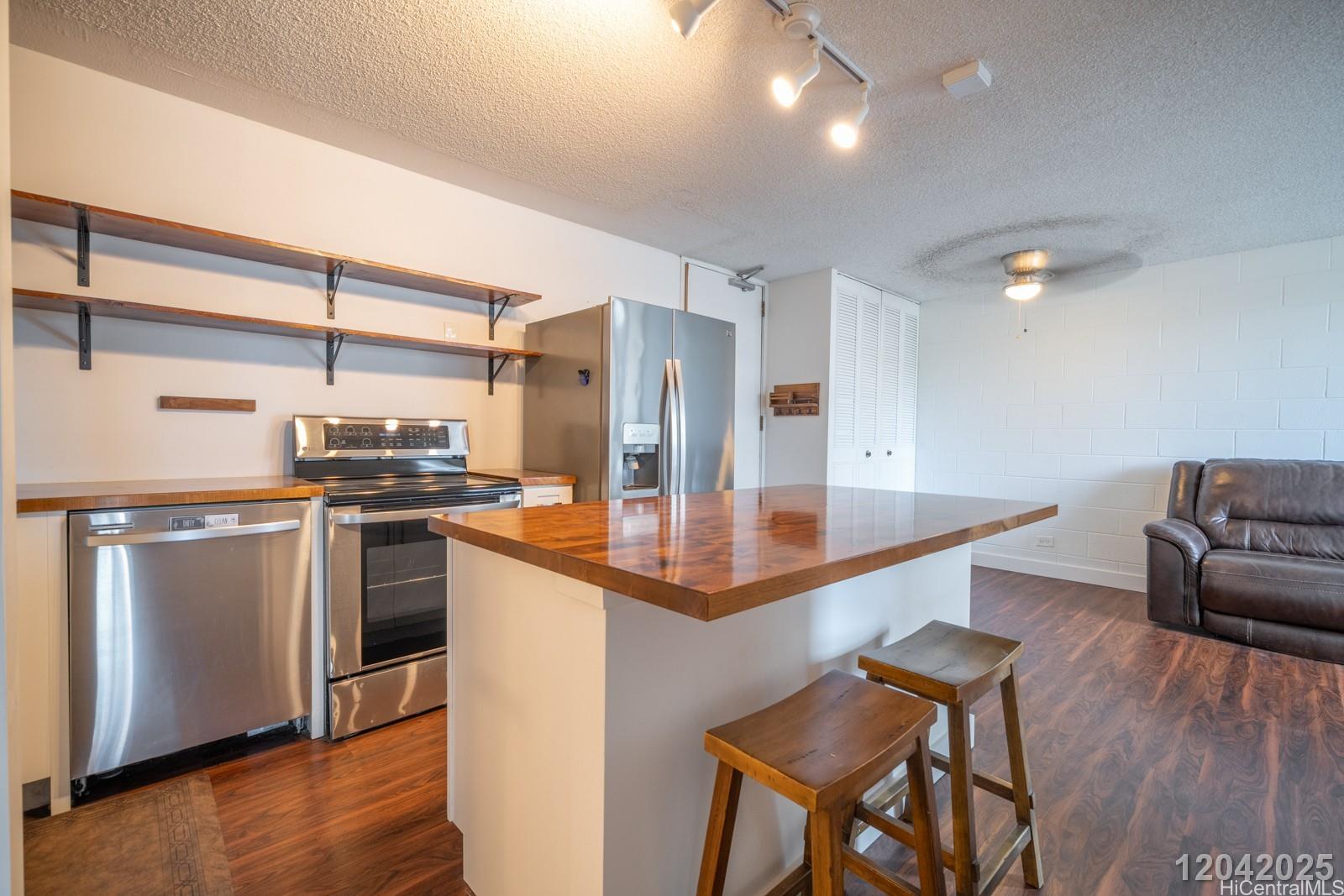 1415 Punahou Street, Unit 306 Honolulu, HI 96822 - Photo 10 of 19 a kitchen with stainless steel appliances kitchen island granite countertop a table chairs in it and wooden floors