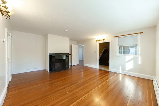 a view of empty room with wooden floor and fireplace
