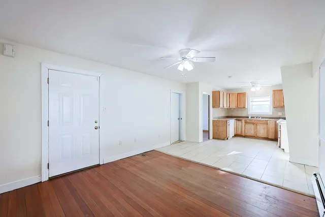 a view of an empty room with a window and wooden floor