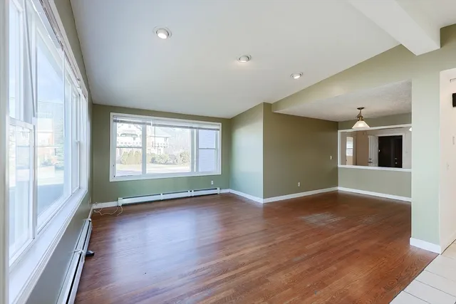 a view of an empty room with a window and wooden floor