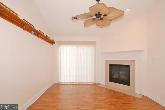 a view of an empty room with a chandelier fan and a fireplace