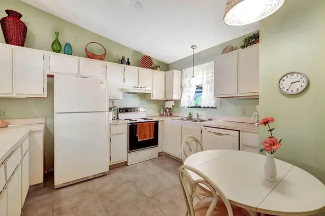 a kitchen with stainless steel appliances granite countertop a refrigerator sink and white cabinets