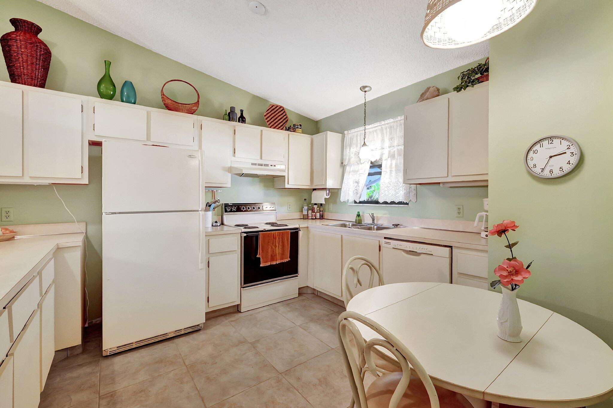 3001 Southeast Aster Lane, Unit 906 Stuart, FL 34994 - Photo 7 of 24 a kitchen with stainless steel appliances granite countertop a refrigerator sink and white cabinets