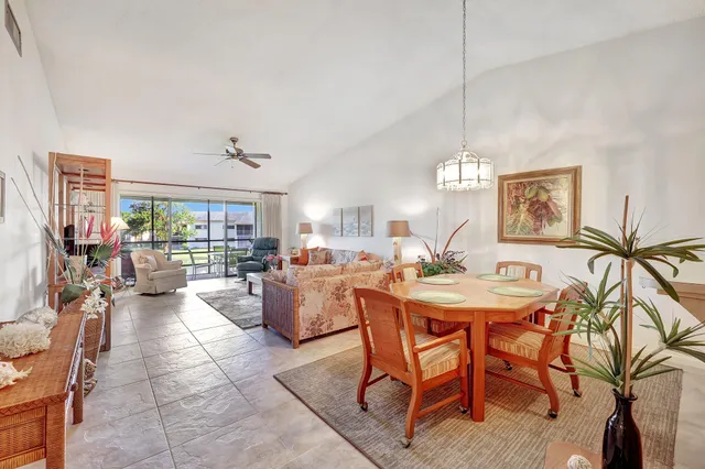 a view of a dining room and livingroom with furniture wooden floor a rug a painting and a chandelier