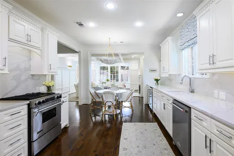 a kitchen with stainless steel appliances granite countertop a stove a sink dishwasher a microwave oven and a dining table with wooden floor