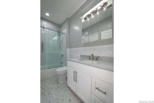 a bathroom with a toilet a sink a mirror and a shower