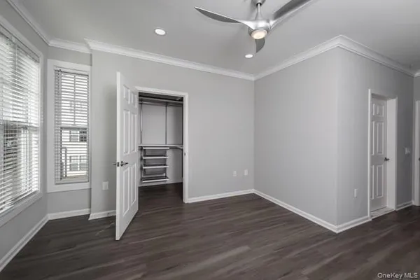 an empty room with wooden floor ceiling fan and windows