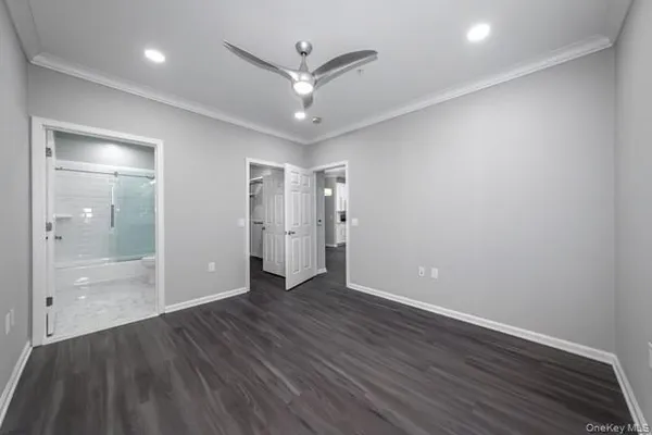 an empty room with wooden floor and a ceiling fan