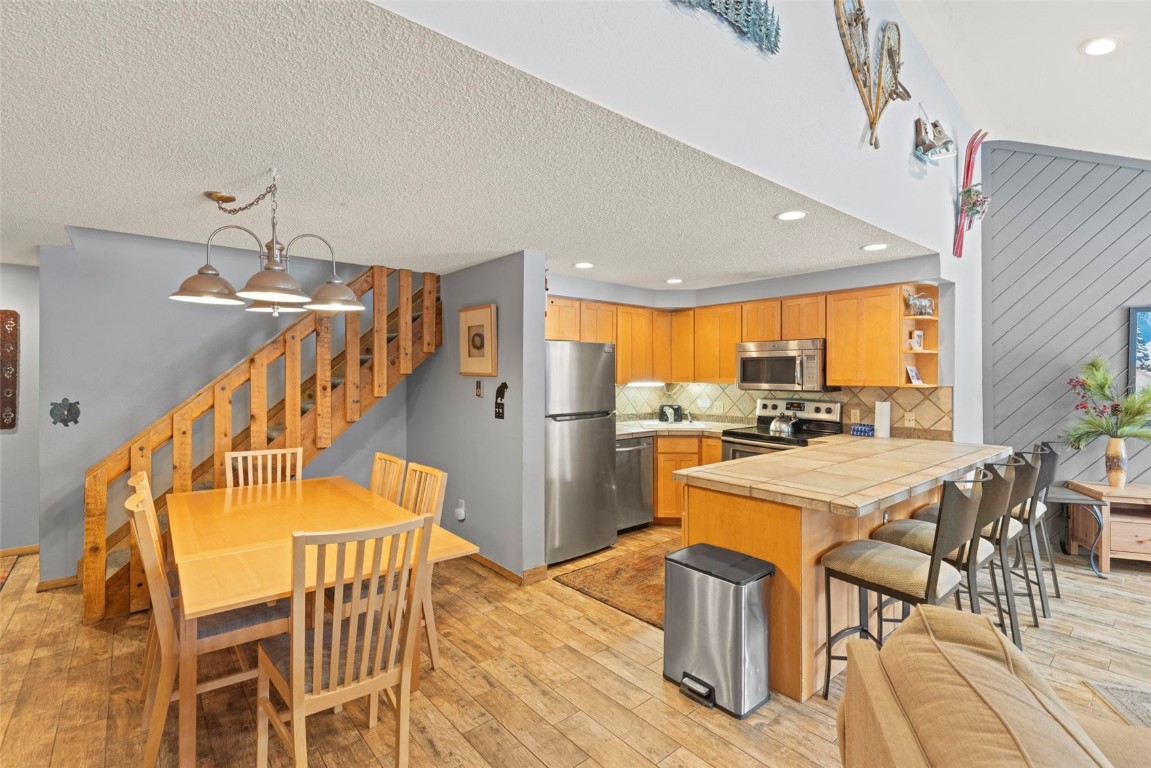405 4 O Clock Road, Unit 12F Breckenridge, CO 80424 - Photo 11 of 43 Kitchen with pendant lighting, tile countertops, backsplash, light LVP flooring, and stainless steel appliances