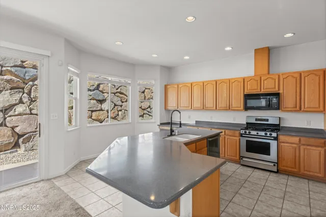 a kitchen with stainless steel appliances granite countertop a sink a stove top oven a counter space and cabinets