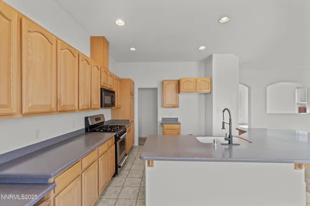 a kitchen with kitchen island granite countertop a sink a counter top space appliances and cabinets